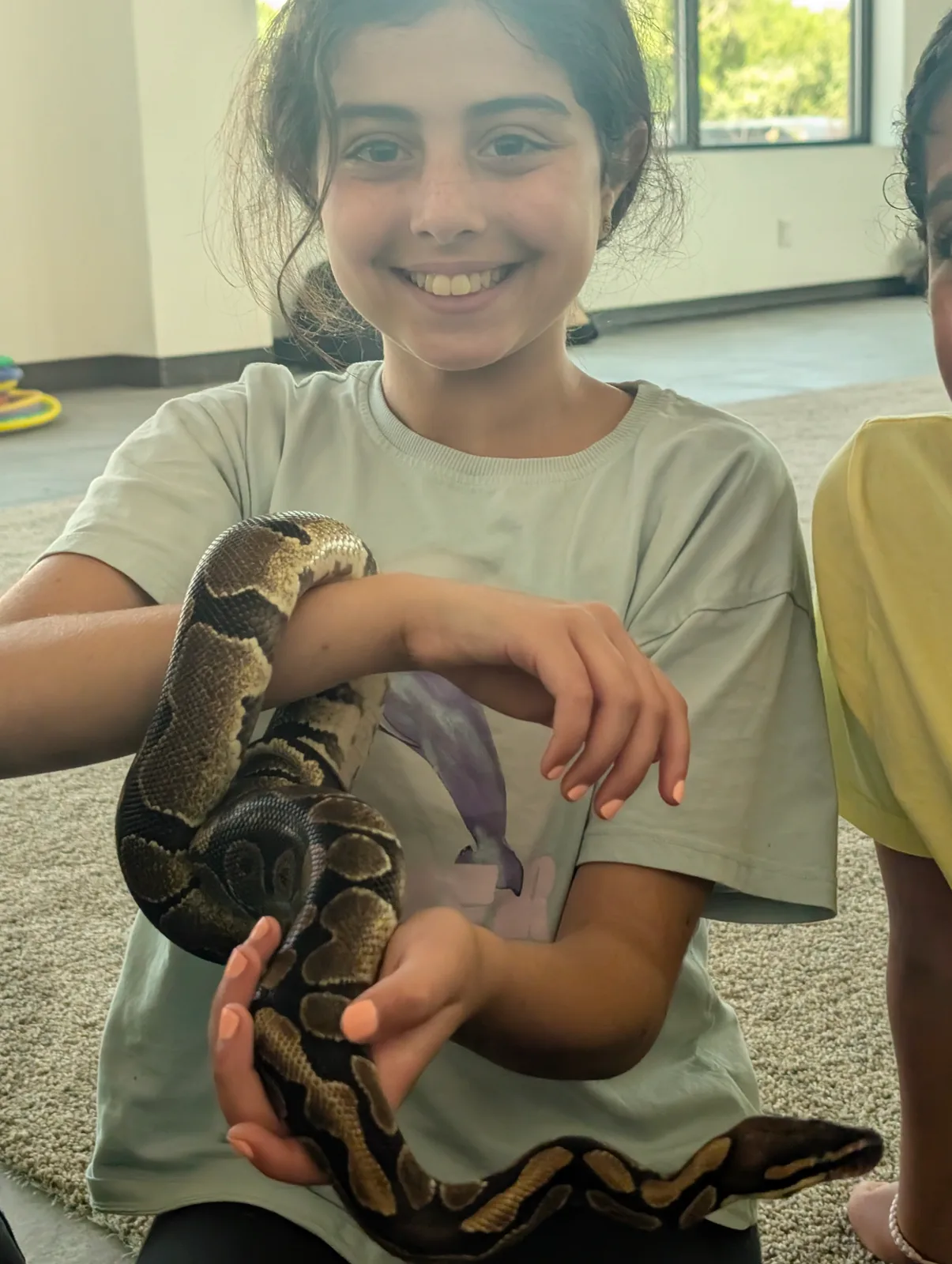A smiling guest holding a large patterned snake